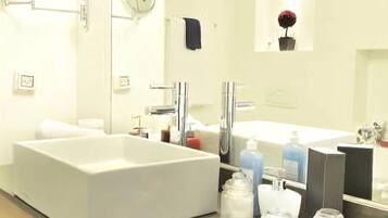 Un baño moderno con una bañera blanca grande, un lavabo doble y un espejo sobre el lavabo.