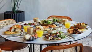 A breakfast table with various dishes, a potted plant, and a wall with the text "CAFÉ FLEUR".