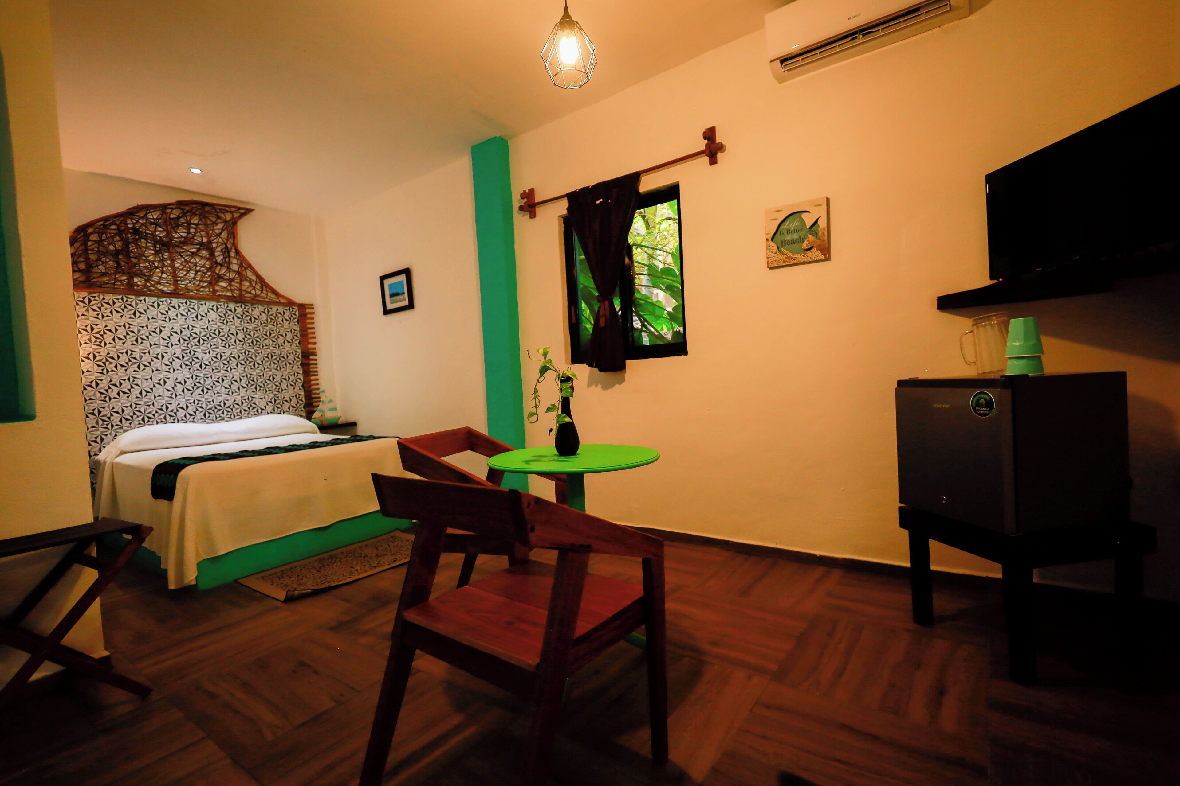 A room with a bed, a desk, a chair, a small table, and a television.