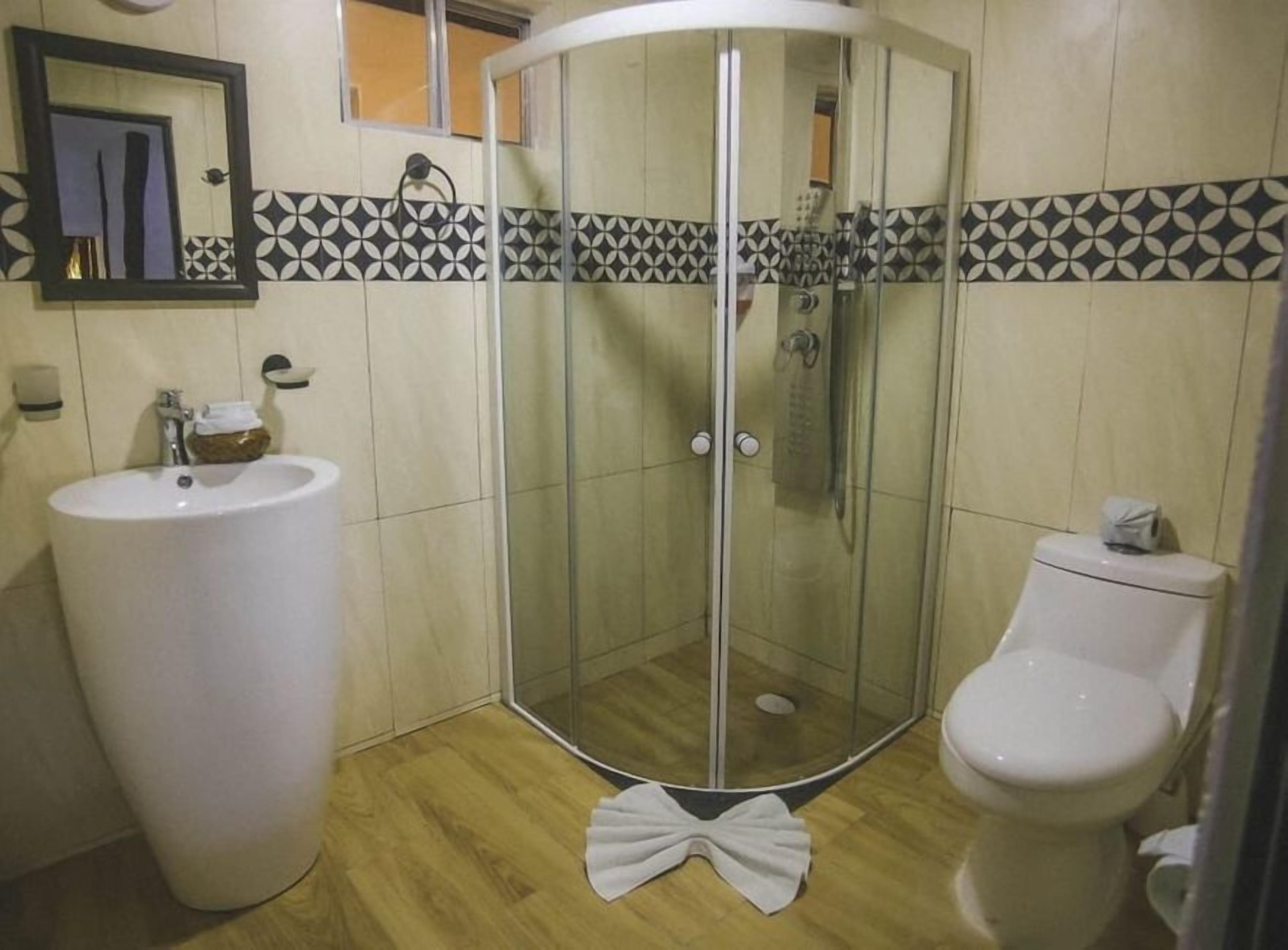 A bathroom with a glass-enclosed shower, a sink, and a toilet.