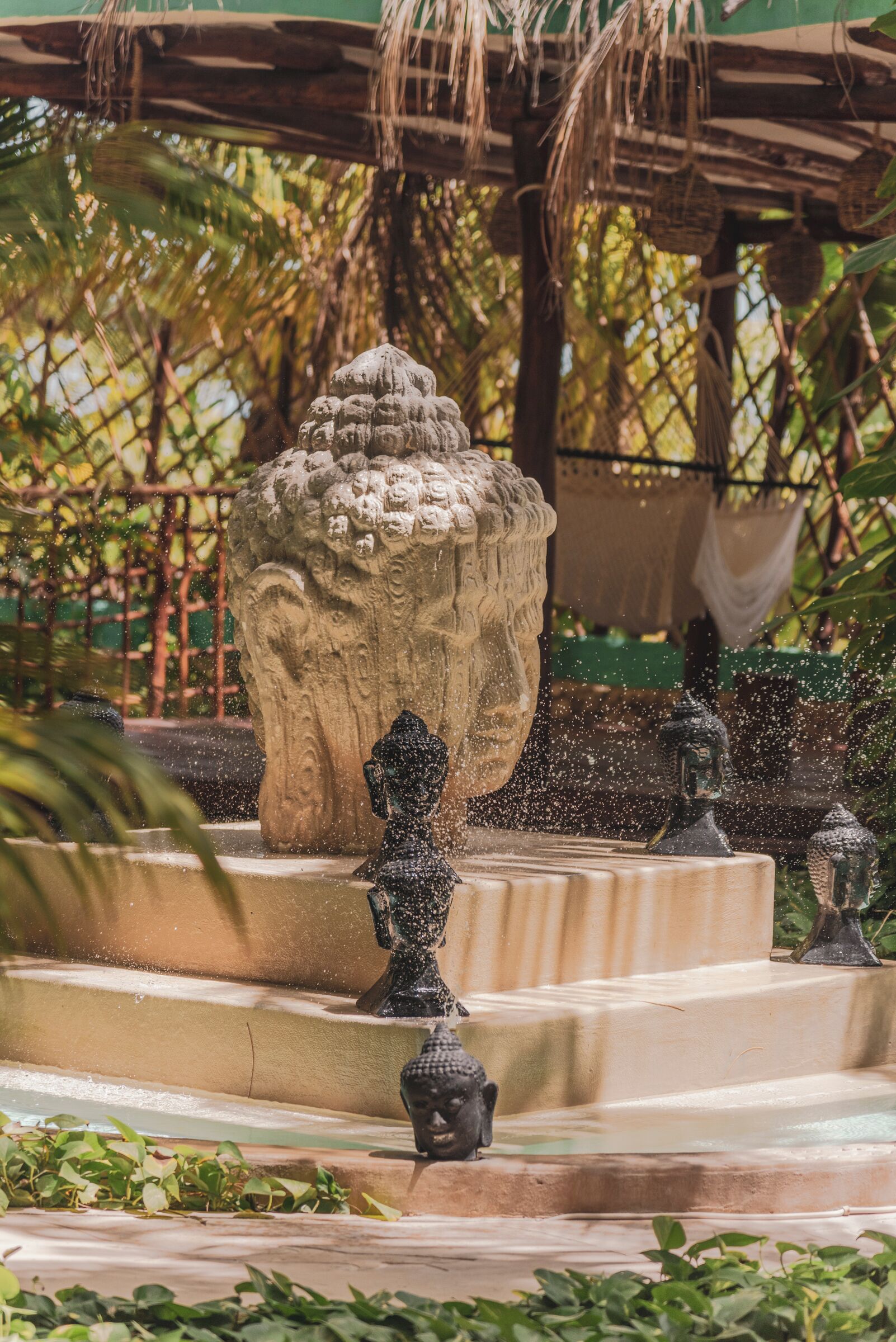 Una estatua de Buda de piedra en un jardín con una fuente de agua.