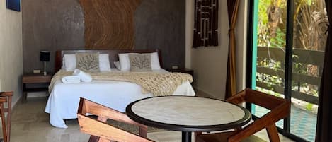 Een moderne slaapkamer met een bed, een ronde tafel met stoelen en een groot raam met gordijnen.
