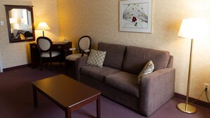 A living room with a sofa, two chairs, a small table, a lamp, a mirror, and a framed picture on the wall. - Auberge La Rocaille (Shawinigan)