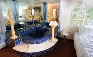 A bathroom with four large tubs, a mirror, a bed, and a wall with a floral mural. - Auberge La Rocaille (Shawinigan)