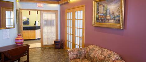 A lobby with a reception desk, a patterned sofa, and a framed painting of a cityscape.