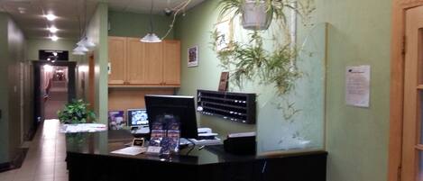 A reception area with a black counter, a computer, and a hanging plant.