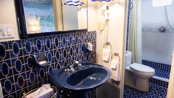 Un baño con un lavabo azul, un espejo, un inodoro y una ducha.