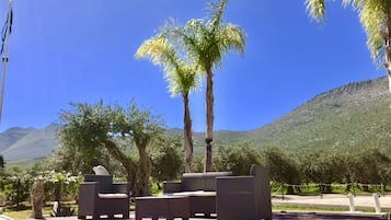 A poolside area with wicker furniture and a view of mountains.