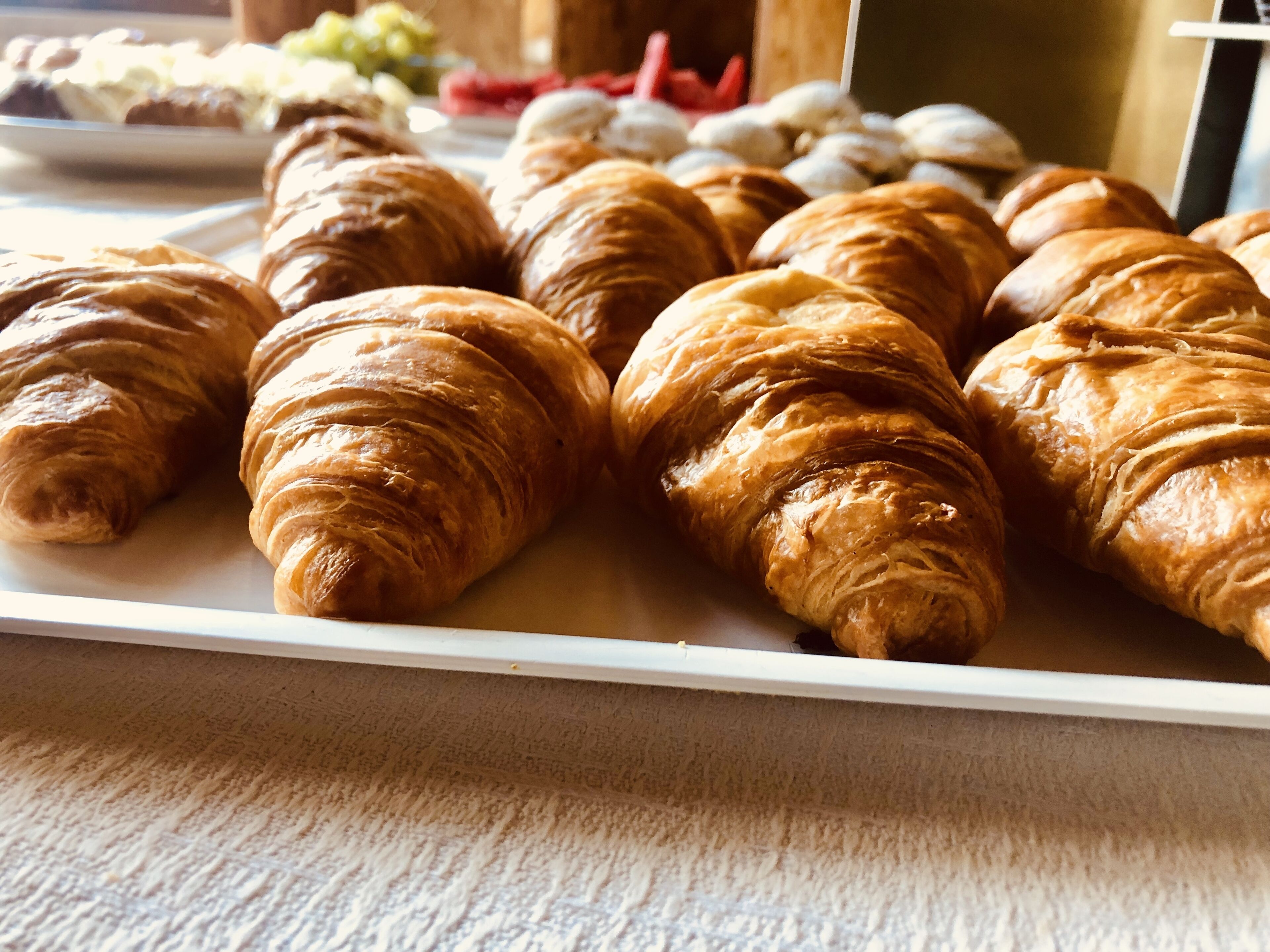 Uma travessa com croissants dourados e crocantes sobre um prato branco.