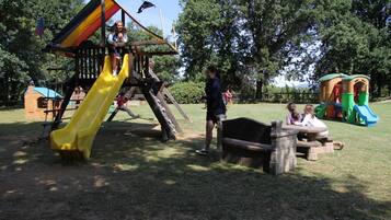 Un parque infantil con un tobogán, estructuras para escalar y mesas de picnic.