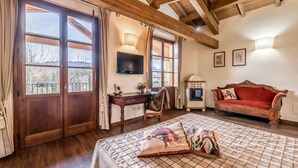 Una habitación con cama, un escritorio de madera, televisor, sofá y chimenea.