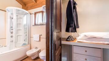 Un baño con bañera, ducha, inodoro y una mesita de noche con lámpara.