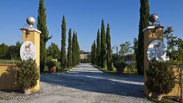 A gravel pathway leading to a building with two columns featuring a horse symbol and the name "Antico Casale".