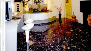 Eine Lobby mit Marmorboden, einer Rezeption, einer dekorativen Decke und einer Tür zu einem anderen Raum.