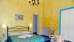 Ein Schlafzimmer mit Bett, Tisch mit Vase, Wandleuchte und Tür.