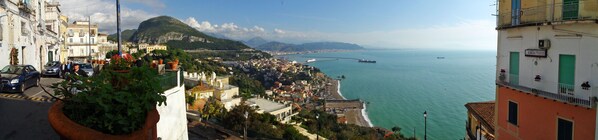 A coastal town with buildings along the waterfront, a view of the sea, and a mountainous backdrop.