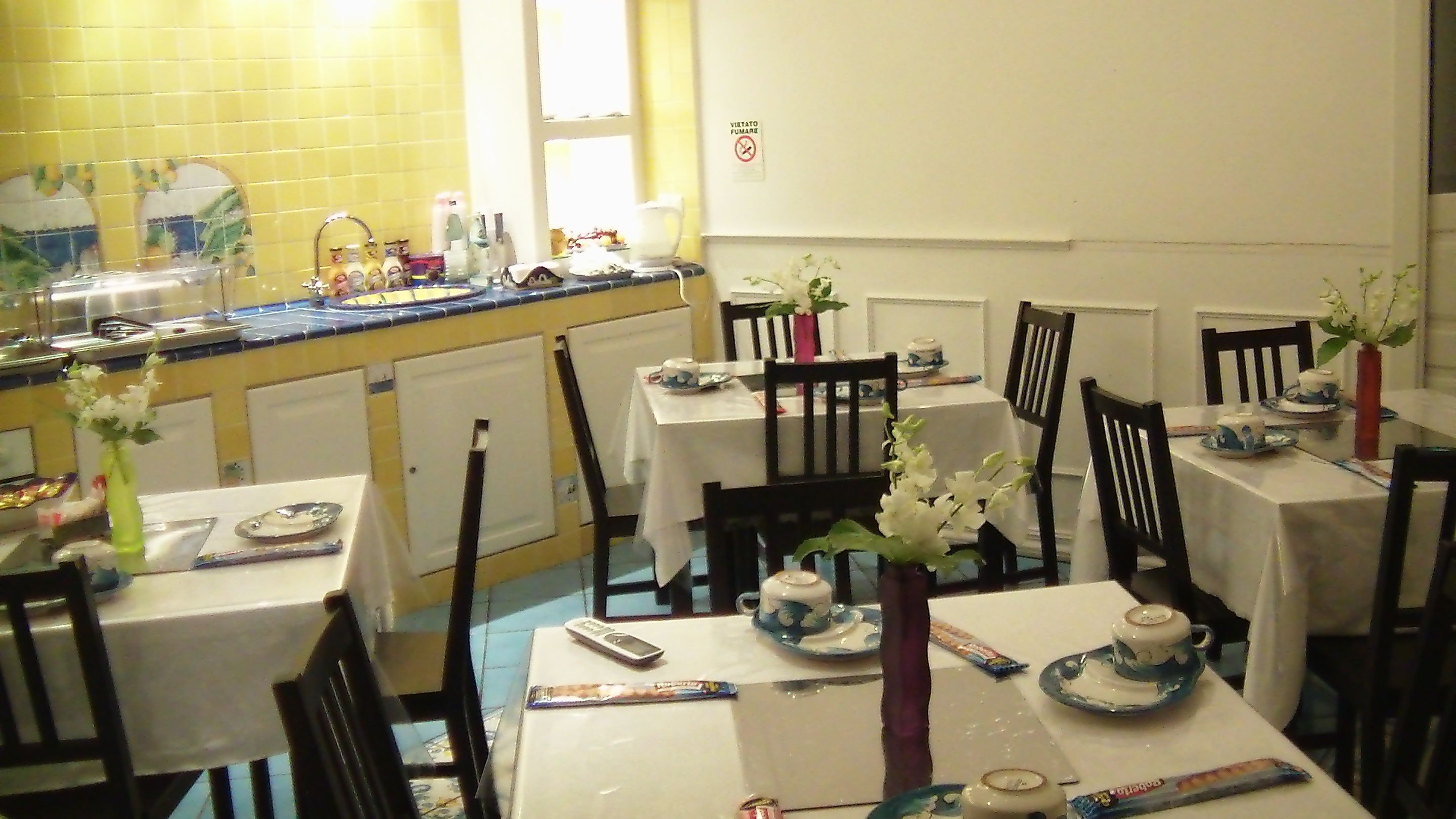 A dining area with multiple tables set for tea service, featuring floral centerpieces and tea sets.