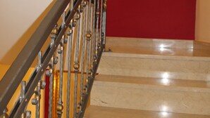 Una escalera con una pared roja y un espejo con marco dorado.