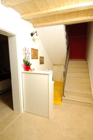 A staircase with a wooden handrail leading to a red wall.