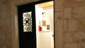 Un edificio de piedra con una puerta negra y un pequeño tramo de escalones que conducen a ella.