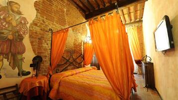 Una habitación con cama con dosel, cortinas naranjas, un mural en la pared y un televisor.