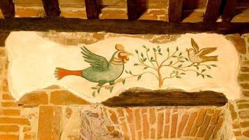 A mural of two birds on a branch, painted on a brick wall.