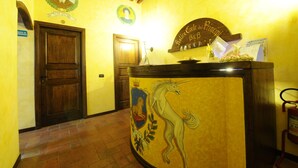 A reception area with a wooden door, a coat of arms, and a fire extinguisher. - Antica Corte dei Principi (Lucca)