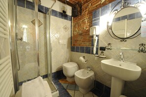 Ein Badezimmer mit Glasdusche, Toilette, Bidet und Waschbecken mit Spiegel darüber.