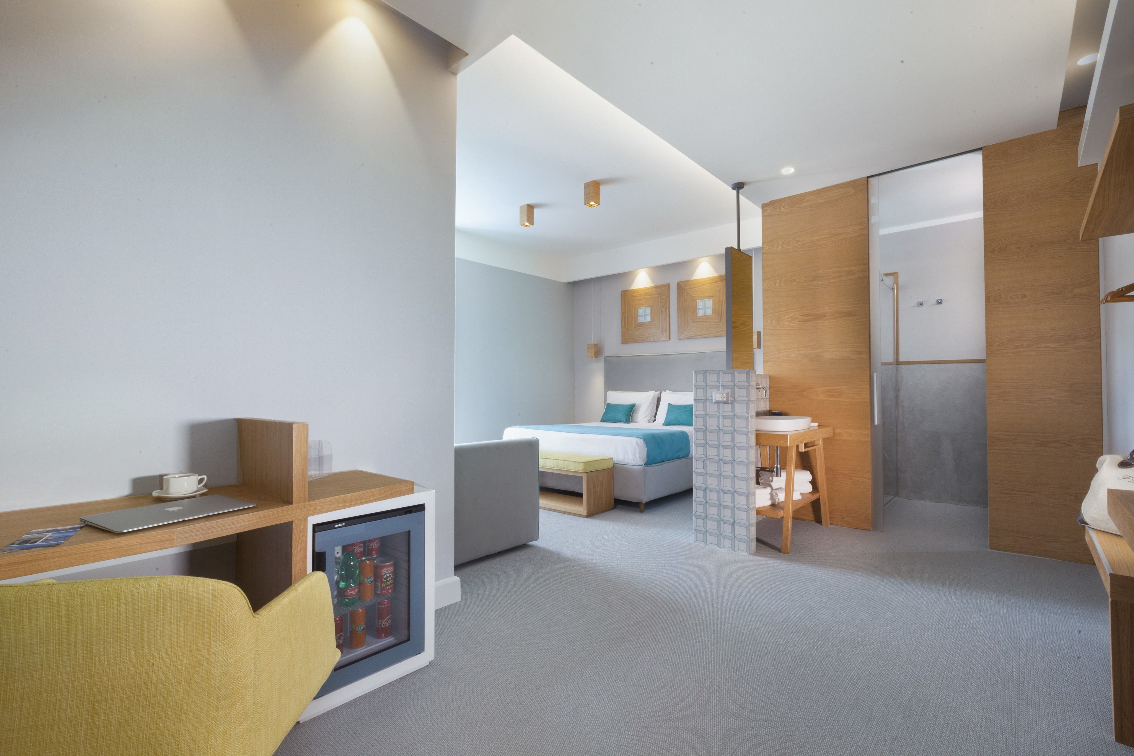Ett modernt hotellrum med skrivbord, stol, säng och ett litet kök.