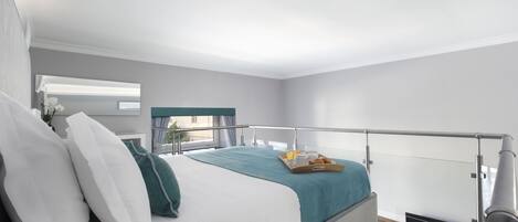A modern bedroom with a bed, a bedside table, a window with curtains, and a balcony railing.