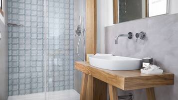 A modern bathroom with a glass shower enclosure, a wooden vanity with a white sink, and a large mirror above the sink.