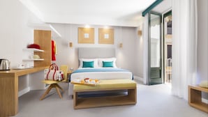 Een moderne hotelkamer met een bed, een bureau, een stoel en een tafeltje met ontbijtartikelen.