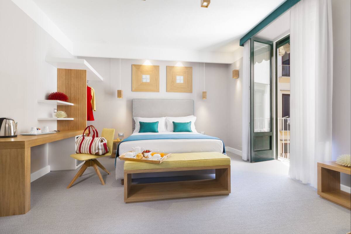 Une chambre d’hôtel moderne équipée d’un lit, d’un bureau, d’une chaise et d’une petite table avec des articles pour le petit-déjeuner.