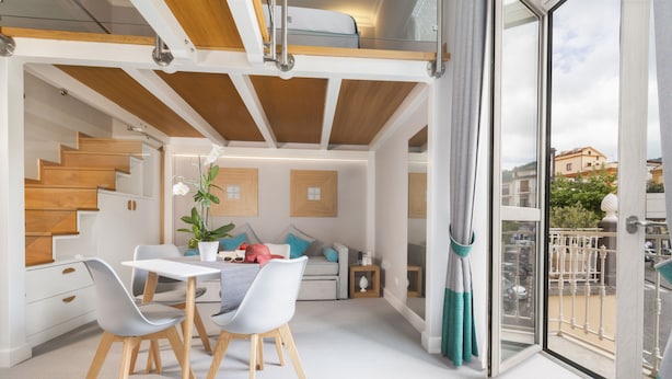 Een modern interieur met een eethoek, trap en balkon met uitzicht over de stad.