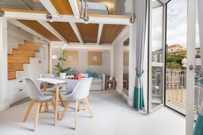 Een modern interieur met een eethoek, trap en balkon met uitzicht over de stad.