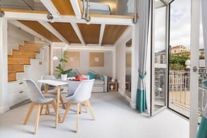 Un interno moderno con zona pranzo, scala e balcone vista città.