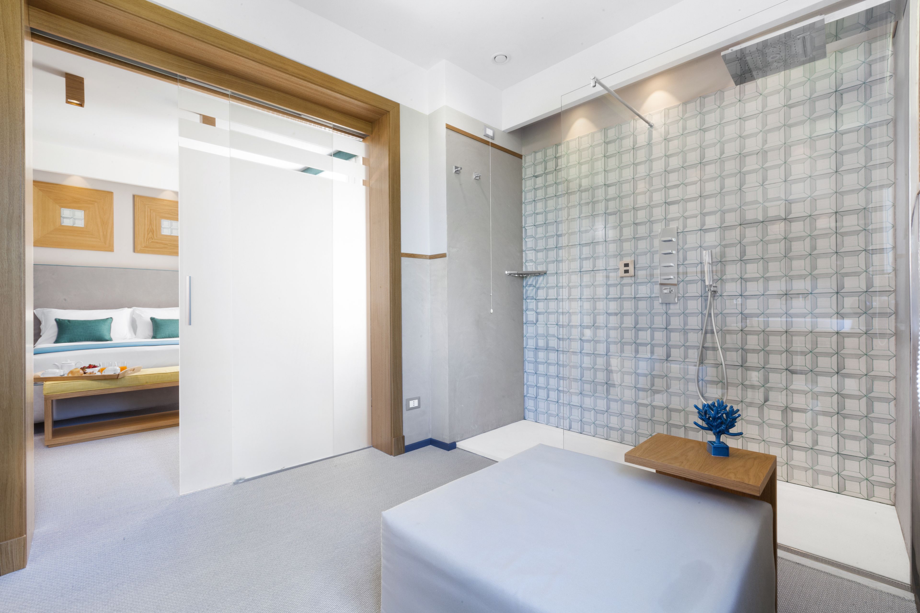 A modern hotel room with a shower, a bed, and a bedside table with a decorative item.