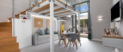 A spacious living area with a staircase, dining table, and seating.