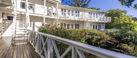 A white multi-story building with a wooden deck and white railings.
