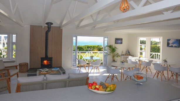 A spacious living area with a fireplace, comfortable seating, and a view of the outdoors. - Brenton Beach House (Knysna)