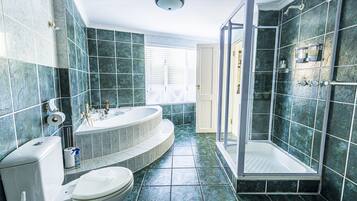 Une salle de bain comprenant des toilettes, une baignoire et un espace douche.
