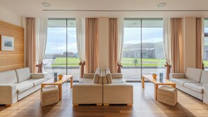 A spacious living room with a large window, a sofa set, a coffee table, and a view of the outdoors.