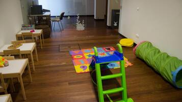 Children can play and learn in this spacious room with a desk, computer, and play area featuring a green ladder and colorful play mat.