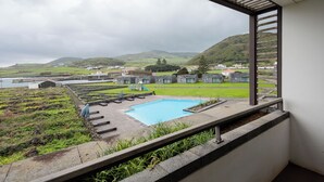 A pool area with a view of a green landscape and buildings in the distance.