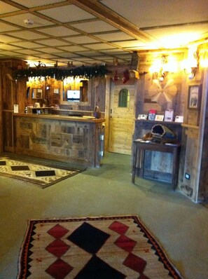 A rustic interior with a stone counter, wooden walls, and a patterned rug. - Hotel Mon Reve (Valtournenche)