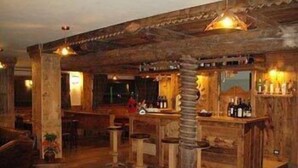 A rustic bar area with wooden furniture and a bar counter. - Hotel Mon Reve (Valtournenche)