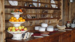 A dining area with a wooden table set for four, surrounded by wooden cabinets and shelves with various dishes and kitchenware. - Hotel Mon Reve (Valtournenche)