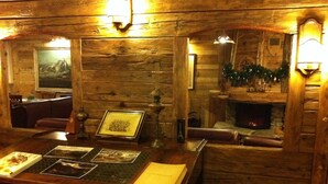 A cozy room with wooden walls, a fireplace, and a table displaying various items. - Hotel Mon Reve (Valtournenche)