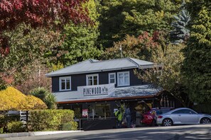 A lodge named Pinewood with a two-story building, a covered entrance, and a parking area with cars.