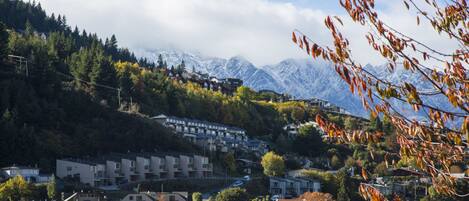 A hillside residential area with multiple apartment buildings, surrounded by trees and mountains in the background.